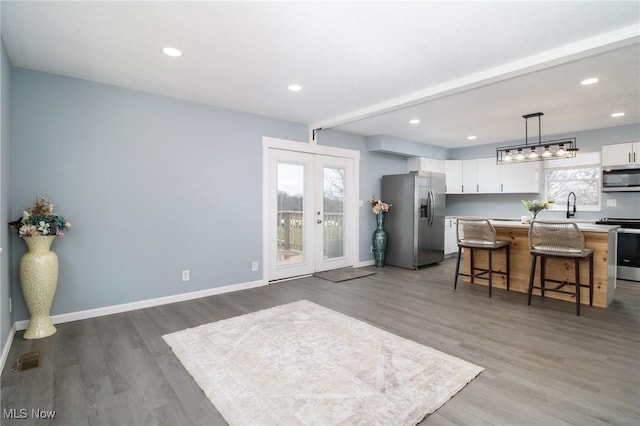 kitchen featuring a kitchen breakfast bar, french doors, stainless steel appliances, white cabinetry, and a kitchen island