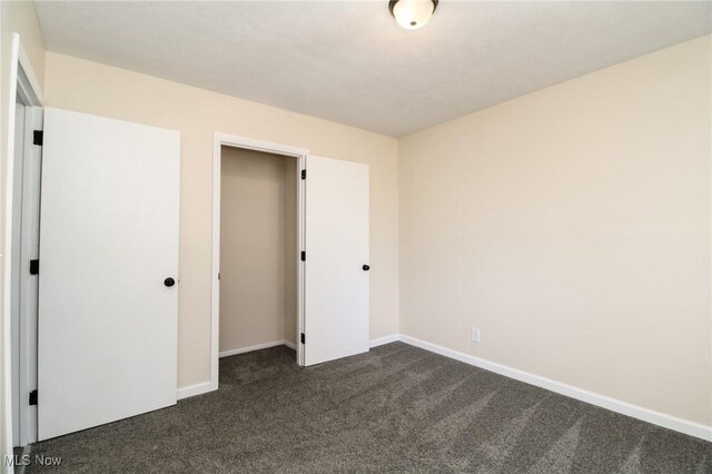 unfurnished bedroom with a closet and dark carpet