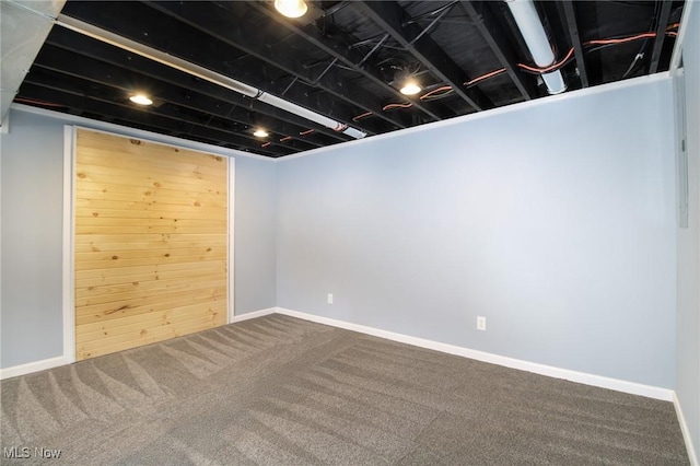 basement featuring carpet flooring and wood walls