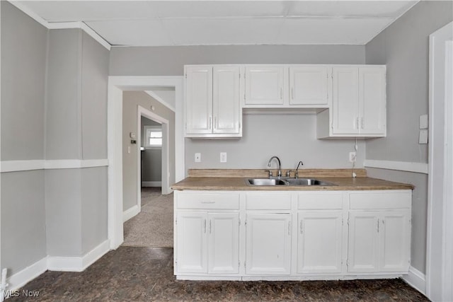 kitchen with sink, white cabinets, and dark carpet