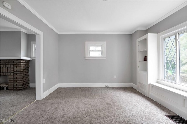 carpeted empty room featuring crown molding, plenty of natural light, and a brick fireplace