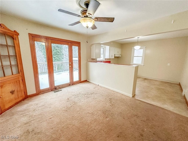 unfurnished living room featuring ceiling fan and light carpet