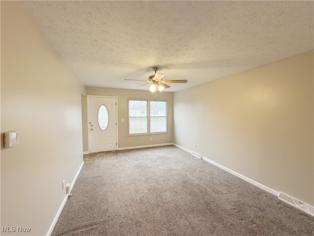 carpeted spare room with ceiling fan and a textured ceiling