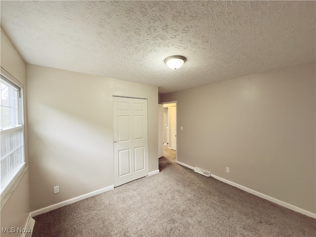 empty room with carpet and a textured ceiling