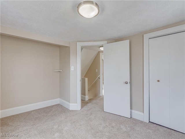 unfurnished bedroom featuring a textured ceiling, light colored carpet, and a closet