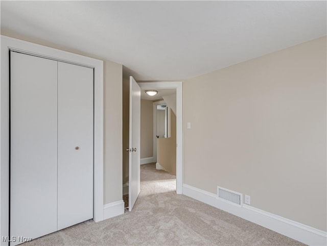 unfurnished bedroom with light carpet and a closet