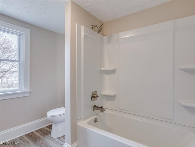 bathroom with plenty of natural light, shower / bathing tub combination, and a textured ceiling