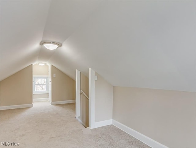 additional living space featuring light colored carpet and vaulted ceiling