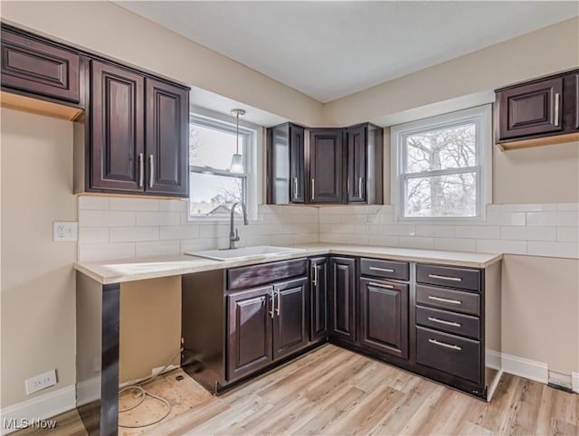 kitchen with light wood-type flooring, dark brown cabinetry, and sink