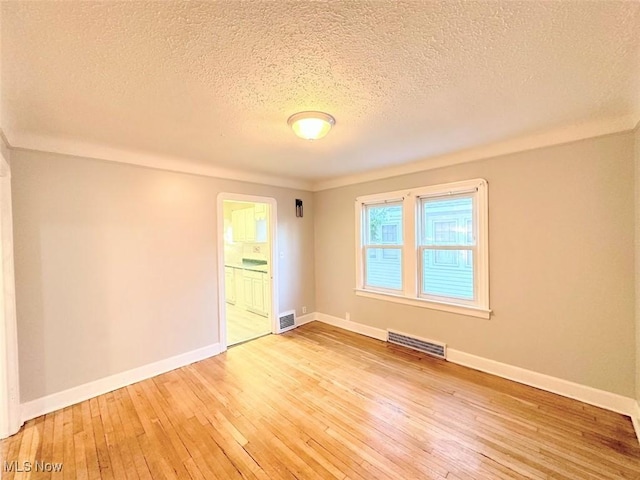 spare room featuring wood-type flooring and a textured ceiling