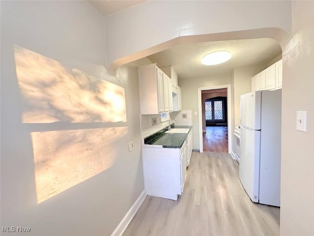 kitchen with white cabinets, white refrigerator, sink, light hardwood / wood-style flooring, and tasteful backsplash