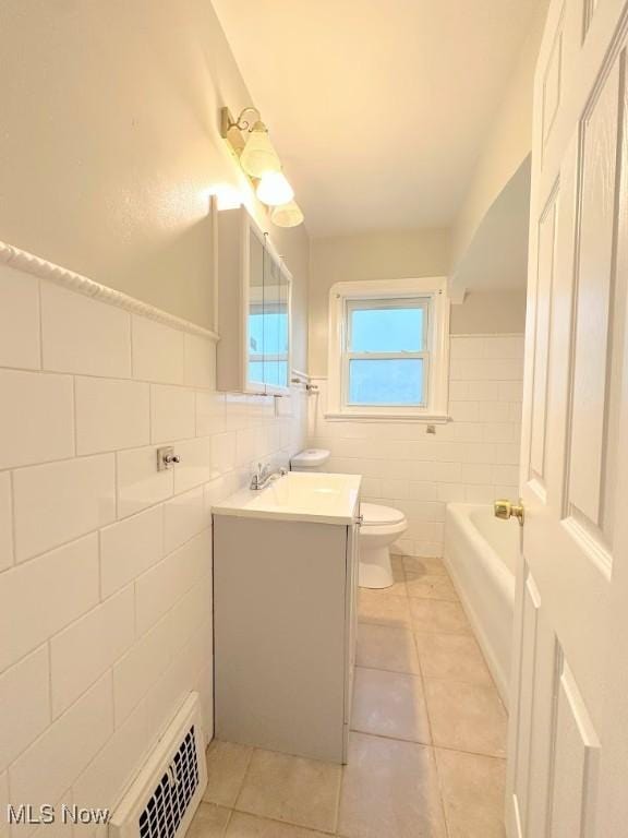 bathroom featuring tile patterned floors, vanity, toilet, and tile walls