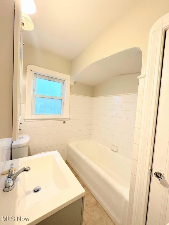 bathroom with sink, tile walls, tile patterned flooring, toilet, and a bathing tub