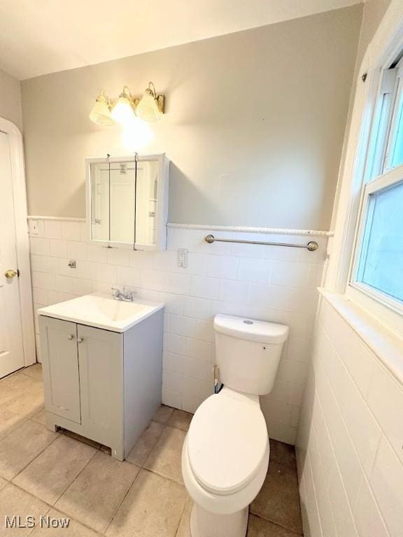 bathroom with tile patterned floors, vanity, toilet, and tile walls