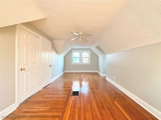 bonus room featuring a textured ceiling, ceiling fan, wood-type flooring, and lofted ceiling