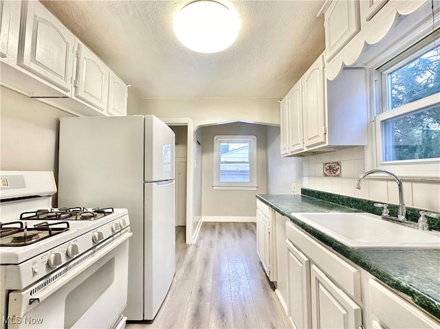 kitchen with light wood-type flooring, white cabinetry, white gas range, and sink