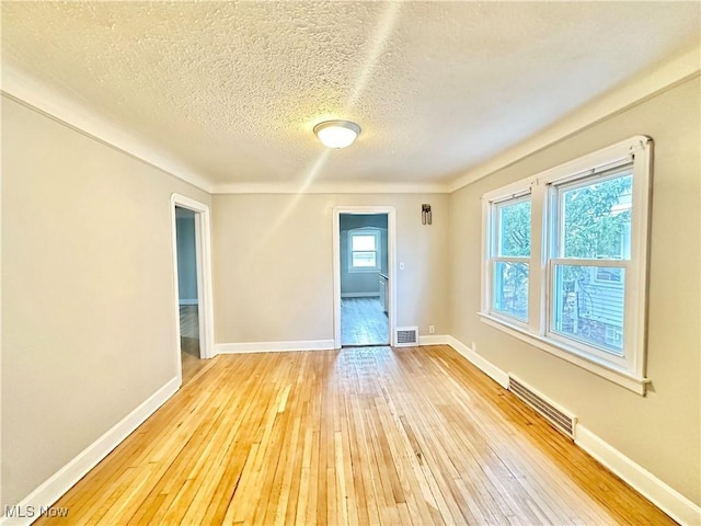 unfurnished room with light hardwood / wood-style floors and a textured ceiling