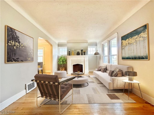 living room with a fireplace, light hardwood / wood-style floors, and a textured ceiling