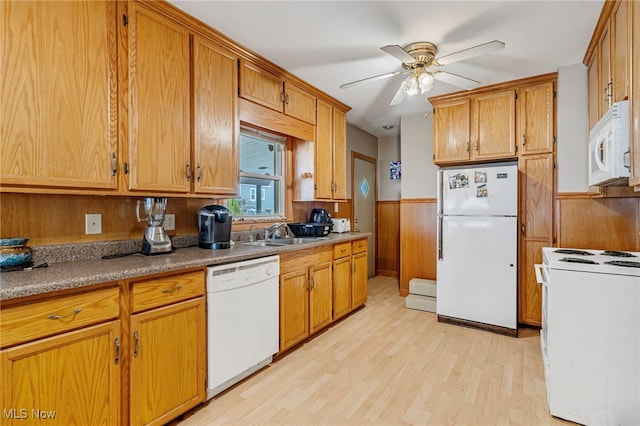 kitchen with ceiling fan, sink, light hardwood / wood-style floors, white appliances, and wooden walls