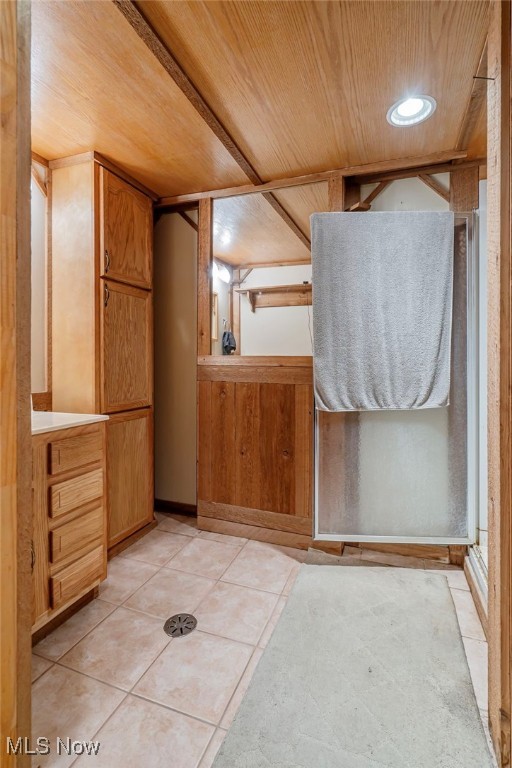 bathroom with wooden walls, tile patterned flooring, wooden ceiling, and an enclosed shower