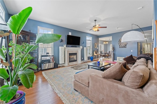 living room featuring hardwood / wood-style floors, ceiling fan with notable chandelier, and a healthy amount of sunlight