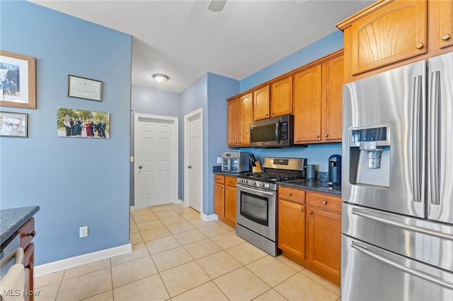 kitchen featuring dark stone countertops, light tile patterned floors, and stainless steel appliances