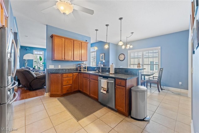 kitchen with light tile patterned floors, kitchen peninsula, hanging light fixtures, and appliances with stainless steel finishes