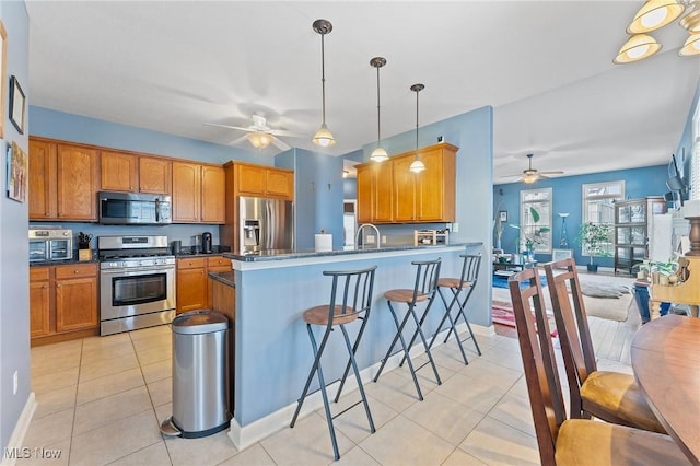 kitchen with kitchen peninsula, pendant lighting, stainless steel appliances, and light tile patterned floors