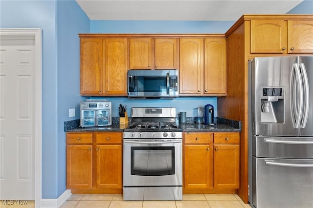 kitchen featuring dark stone counters, light tile patterned floors, and stainless steel appliances