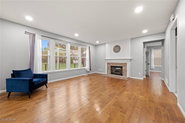 living room with light wood-type flooring and a brick fireplace