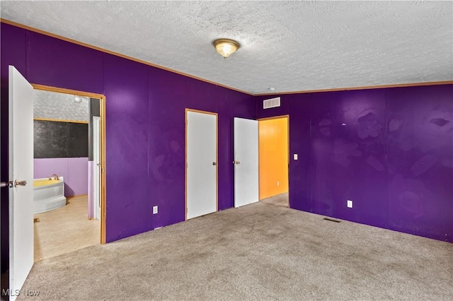 unfurnished bedroom featuring ensuite bath, carpet, and vaulted ceiling