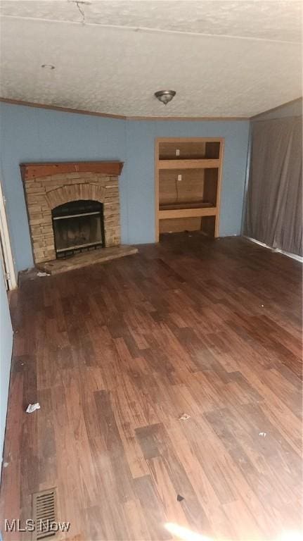 unfurnished living room featuring built in shelves, wood-type flooring, and a fireplace