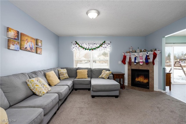 living room with a tile fireplace, a textured ceiling, and carpet flooring