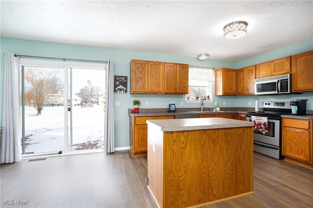 kitchen featuring appliances with stainless steel finishes, a center island, dark hardwood / wood-style floors, and plenty of natural light