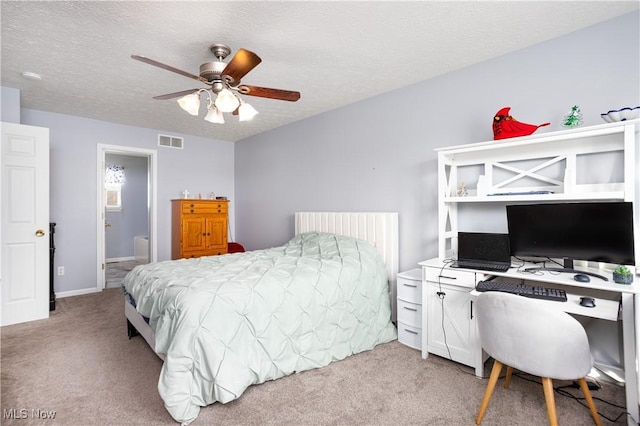 bedroom with light carpet, a textured ceiling, ceiling fan, and connected bathroom