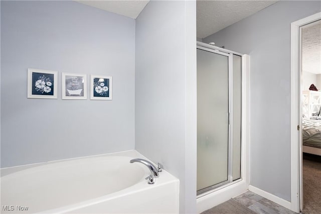 bathroom featuring a textured ceiling and separate shower and tub