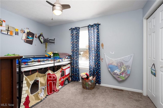 carpeted bedroom featuring ceiling fan, a closet, and a textured ceiling