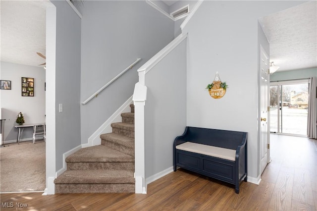 stairway with wood-type flooring, a textured ceiling, and ceiling fan