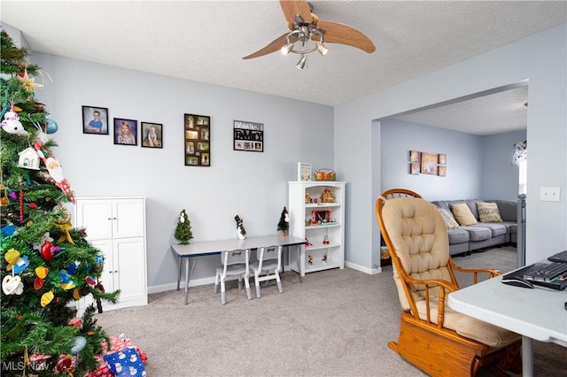 carpeted office space with ceiling fan and a textured ceiling