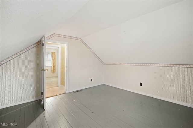 additional living space with hardwood / wood-style floors and vaulted ceiling