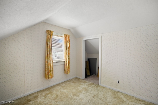 additional living space with light colored carpet and vaulted ceiling