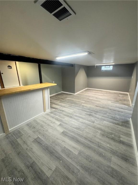 basement featuring visible vents, baseboards, and wood finished floors