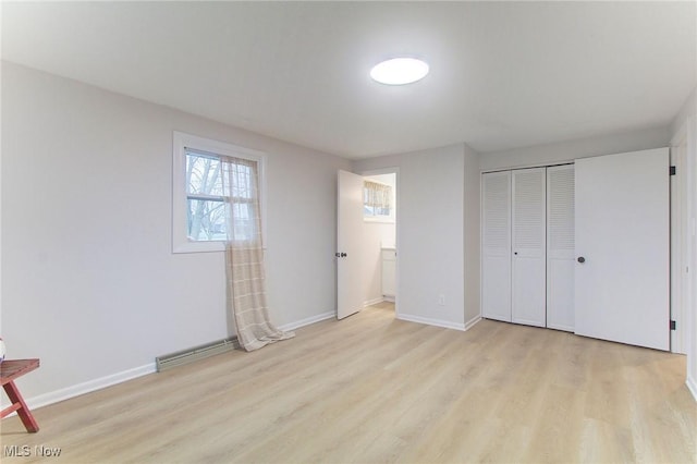 unfurnished bedroom with light hardwood / wood-style floors, a baseboard radiator, and a closet