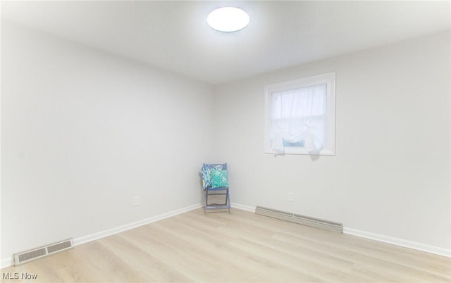 unfurnished room with light hardwood / wood-style floors and a baseboard heating unit