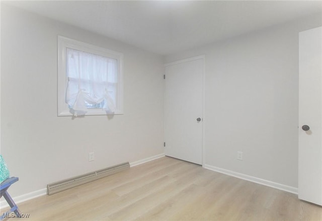 unfurnished room with light hardwood / wood-style floors and baseboard heating