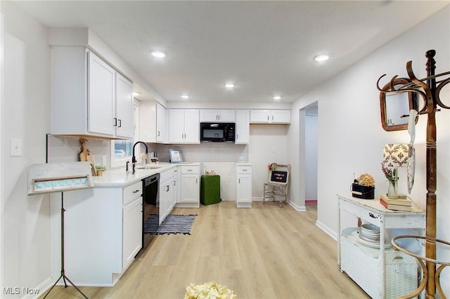 kitchen featuring sink, backsplash, white cabinets, black appliances, and light wood-type flooring