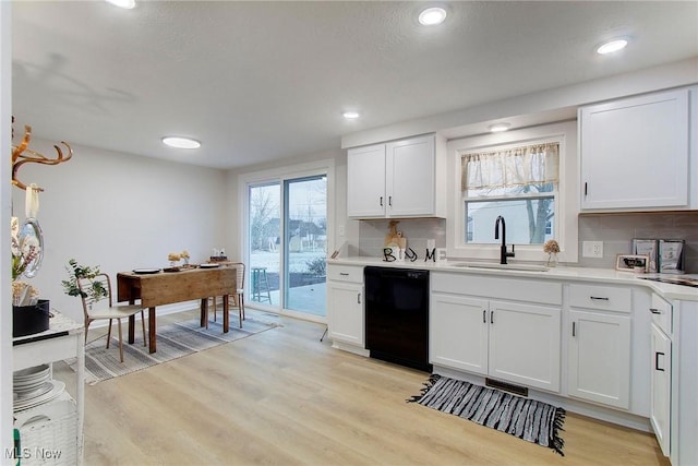 kitchen with white cabinets, sink, black dishwasher, tasteful backsplash, and light hardwood / wood-style floors