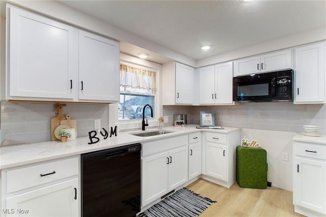 kitchen with black appliances, white cabinets, light wood-type flooring, and sink