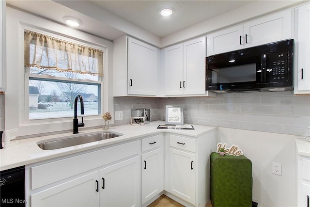 kitchen with light stone countertops, backsplash, sink, black appliances, and white cabinets