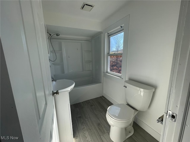 bathroom with hardwood / wood-style floors, toilet, and shower / tub combination